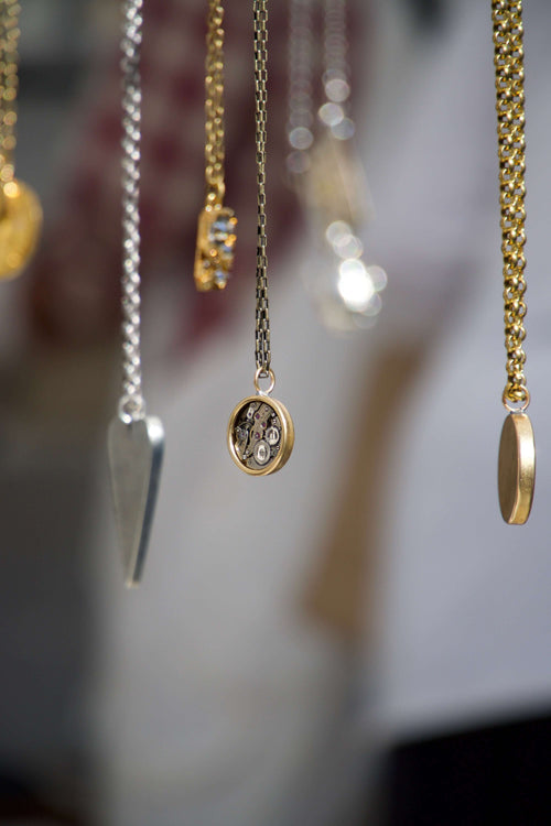 Gold and silver necklaces hanging from above with a blurry background