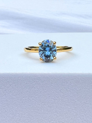 front view of blue gray moissanite ring in yellow gold band